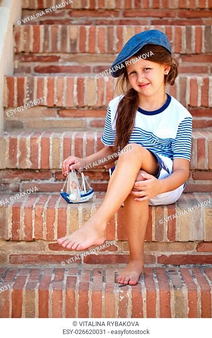 Portrait of beautiful Italian girl in blue cap sitting on stairs