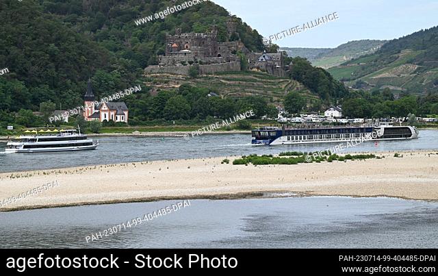 14 July 2023, Hesse, Assmannshausen: Near Rheinstein Castle (back right) and the Clemens Chapel, the excursion ship ""Ehrenfels"" (l) and the cruise ship...