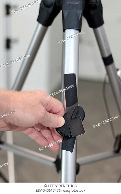 Fingers display camera remote control on tripodal. Hand holds camera remote control taped to a tripod Male hand showing camera remote control black gaff taped...