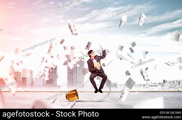 young businessman with a book. flying around papers in chaos
