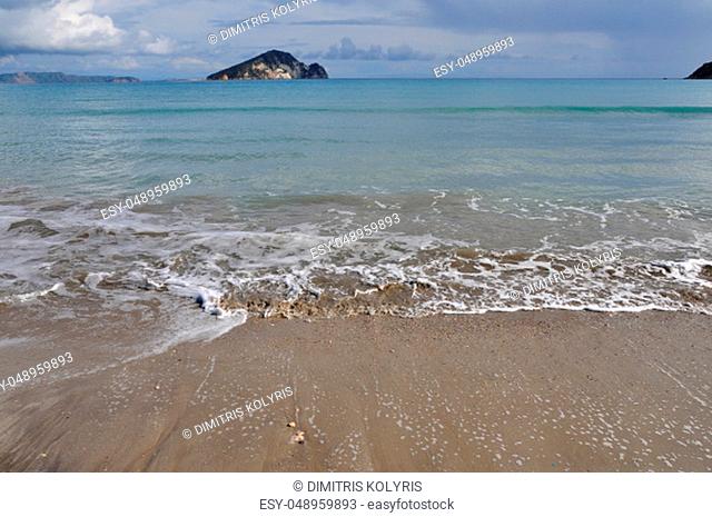 Waves splashing on sandy beach Keri in Zakynthos Greece and Marathonisi island natural habitat of the caretta-caretta sea turtle