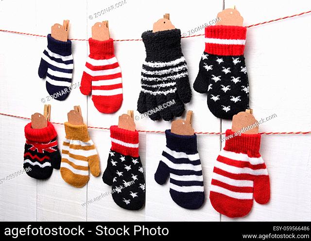 Christmas Advent Calendar: Mitten and Gloves hanging on string and clothes pins against a white wall. Blank tags are in the mittens ready for your copy