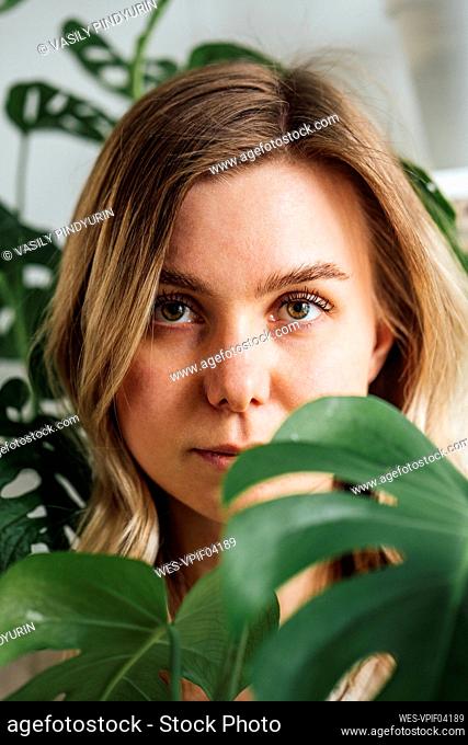 Beautiful woman seen through leaves at home