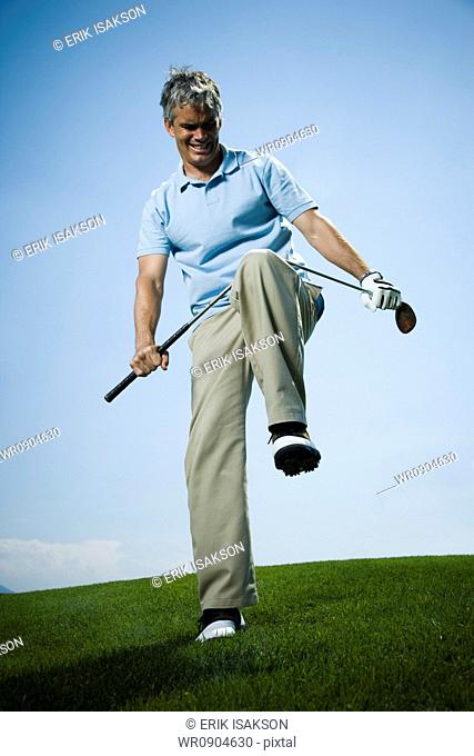 Low angle view of a man breaking a golf club