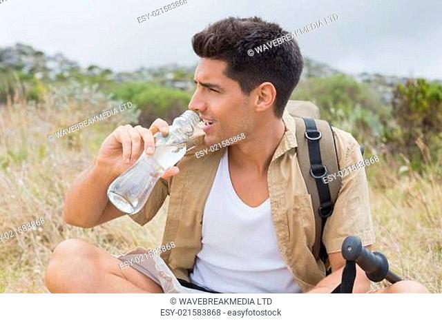 Hiking man drinking water on mountain terrain