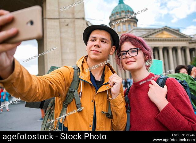 Young couple of tourists taking selfies against the Kazan cathedral in Saint Petersburg - close up
