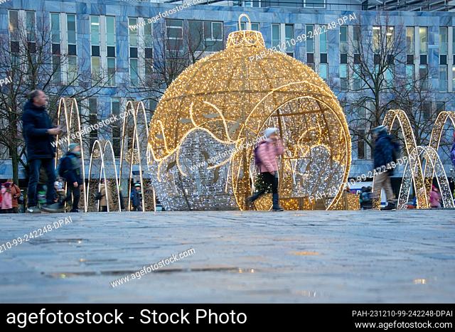07 December 2023, Magdeburg: Teachers and pupils walk across the cathedral square with the Christmas sculptures of the Magdeburg World of Lights in rainy...