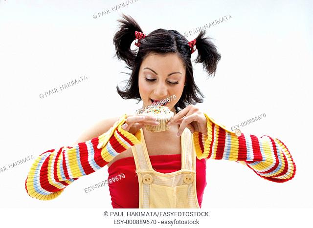 Beautiful Latina girl licking a cupcake, isolated