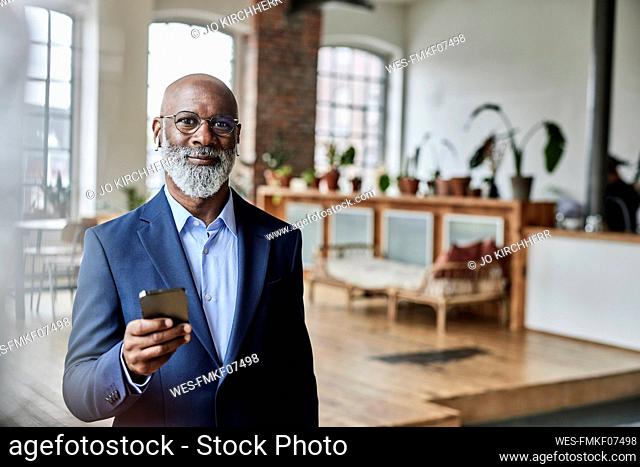 Mature businessman with smart phone at home