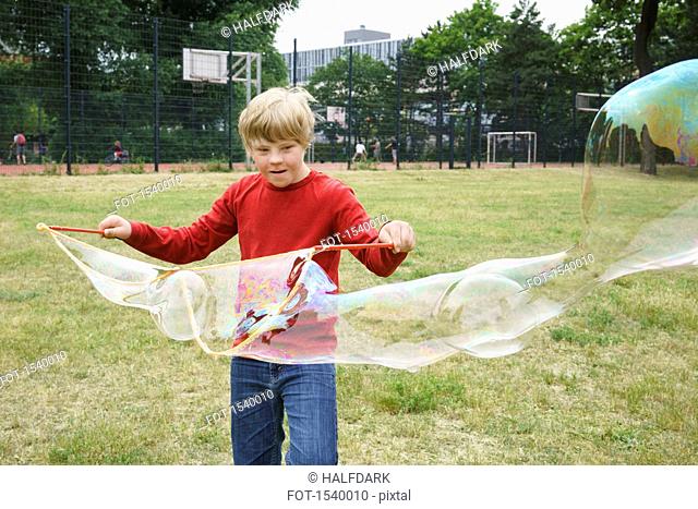 Boy playing with soap bubbles in park