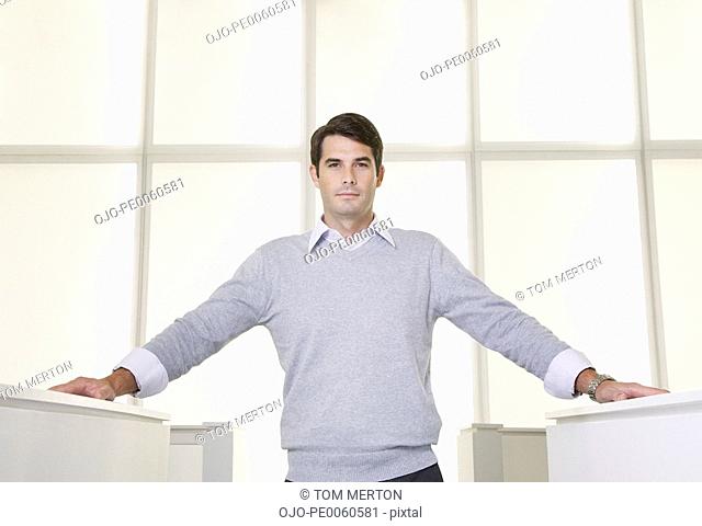 Businessman standing in an office between cubicles