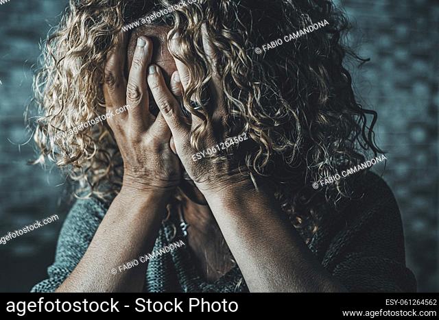 Close up of desperate woman with hands on face in the dark at home. Family gender violence crime situation. Stressed and scared female crying