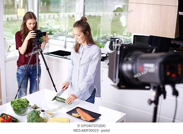 Woman recording her friend while chopping a courgette