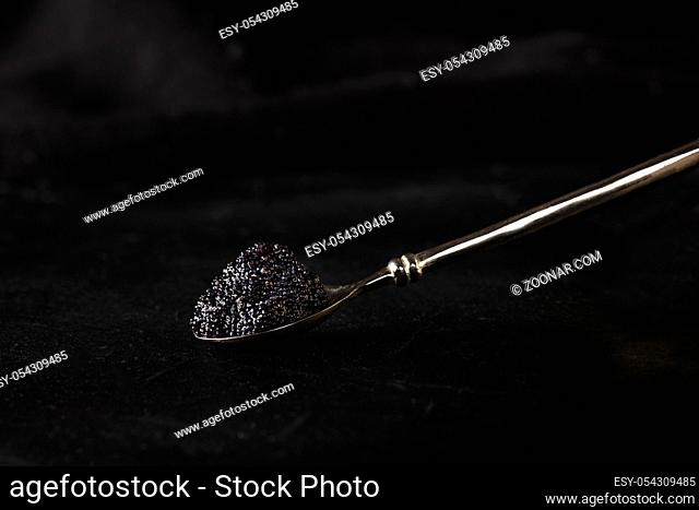 Black caviar on a spoon, on a dark background with copy space. Gourmet food