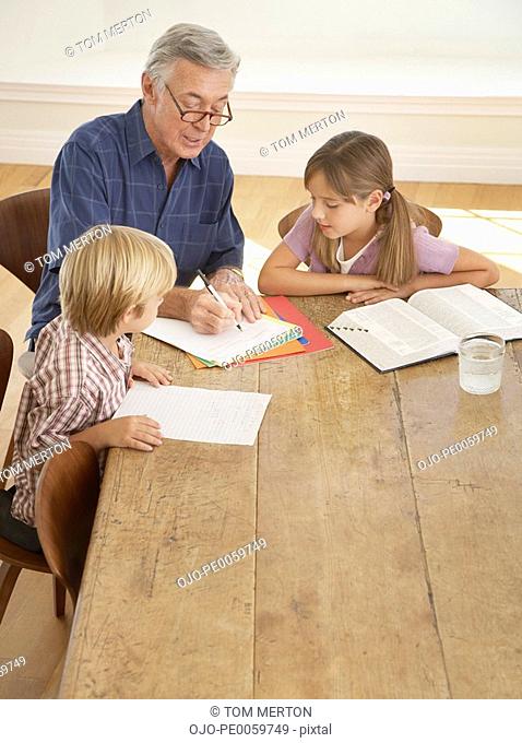 Man helping two kids with homework at kitchen table