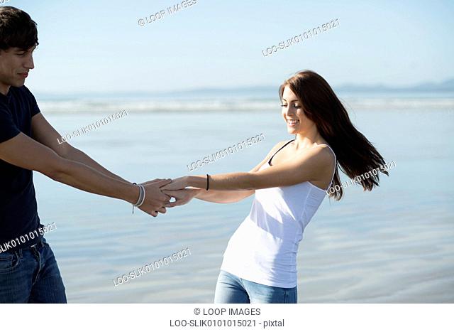 A young couple holding hands on the beach at Porthmadog