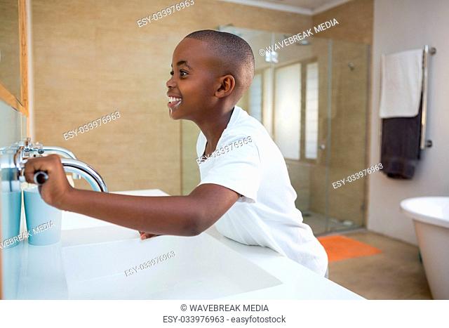 Side view of smiling boy with toothbrush looking at mirror