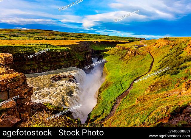 Sunny summer day. Huge masses of water crash down into a narrow gorge. The most picturesque waterfall in Iceland - Gullfoss