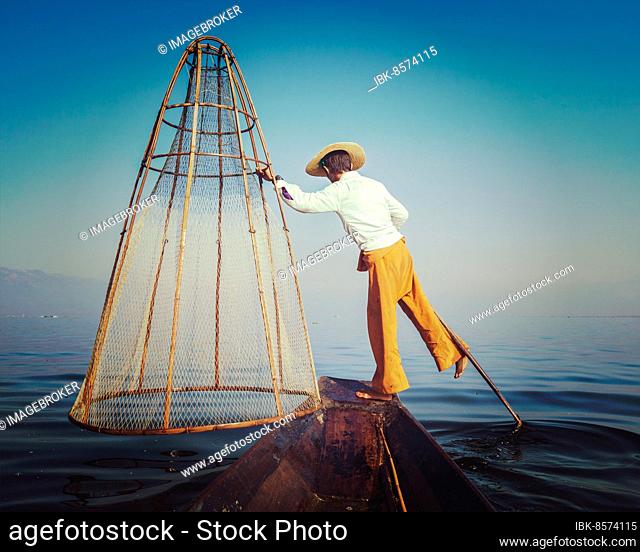 Vintage retro effect filtered hipster style image of Myanmar travel attraction. Traditional Burmese fisherman with fishing net at Inle lake famous for their...