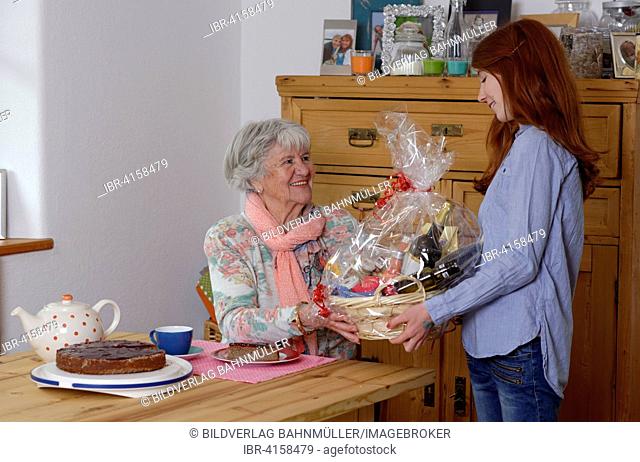 Birthday party, granddaughter congratulating her grandmother with a gift basket, Bavaria, Germany