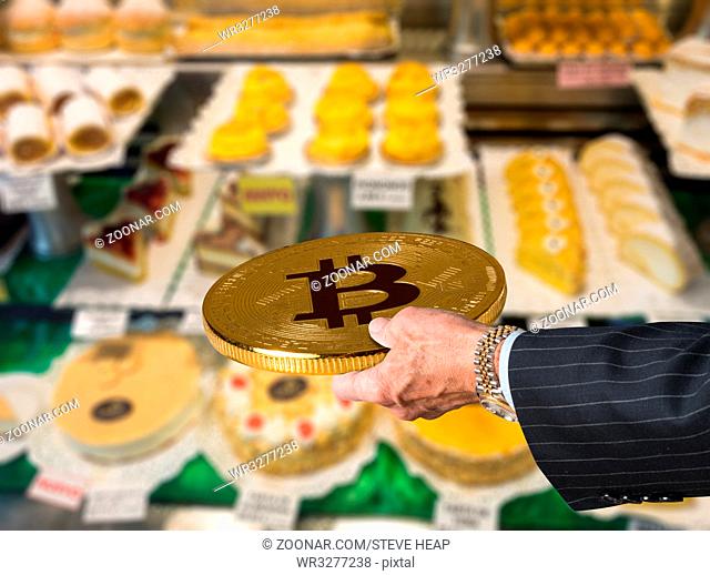 Businessman offering a bitcoin in payment for cakes and flans for sale in window of bakery