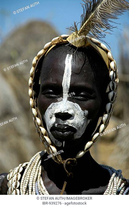 Young Karo tribesman wearing feathers in a headband of Kauri Shells and white paint on his face, portrait, Kolcho, South Omo Valley, Ethiopia, Africa