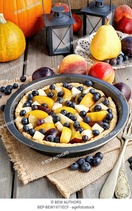Tart with peach, pumpkin, plum, pear and blueberry in autumn setting