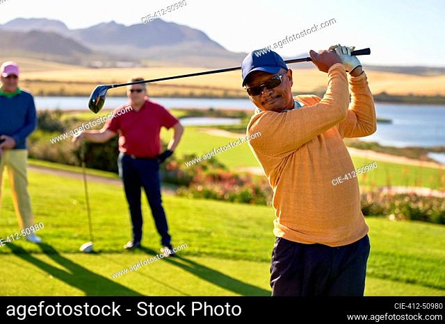 Mature male golfer teeing off at sunny box