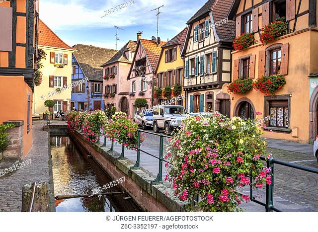 flower decorated brook and old timbered houses with carving, village Ribeauvillé, Alsace, France, location of the Wine Route