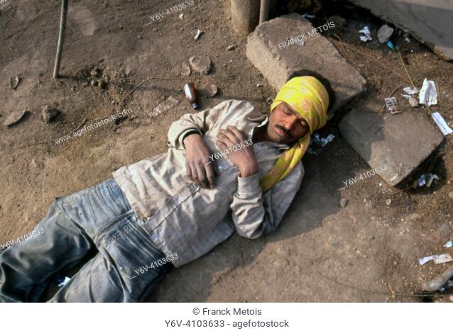A poor man is sleeping on the ground in the street ( Delhi, India)