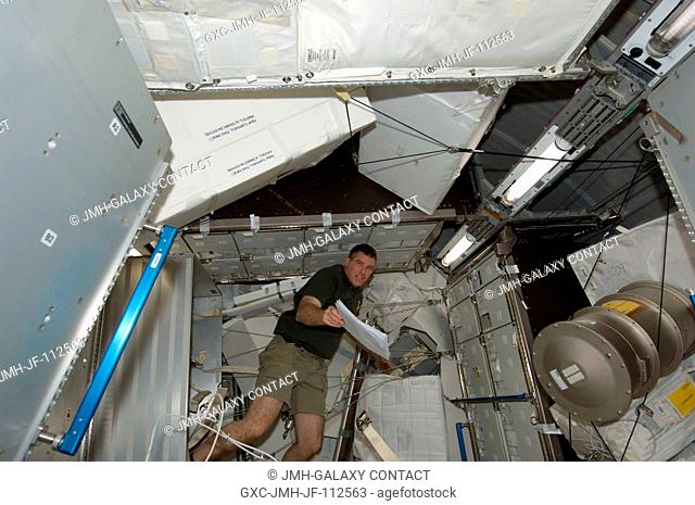 NASA astronaut Steve Bowen, STS-133 mission specialist, works in the Permanent Multipurpose Module (PMM) of the International Space Station while space shuttle...