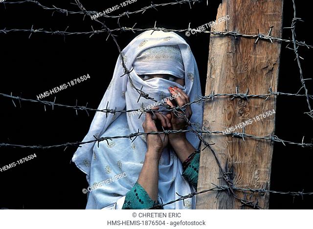 Pakistan, Khyber Pakhtunkhwa, Kalash valleys, Bumburet valley, veiled girl behind the barbed wire from the balcony of her house