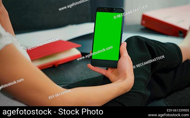 Back View of Woman at Phone with Green Screen for Copy Space. Chromakey Mockup. Girl watching video on couch