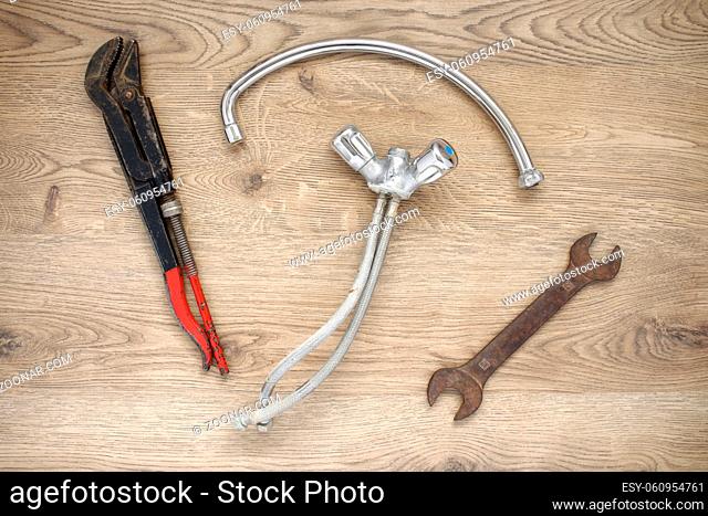 Rusty old plumbing tools and tap on wooden background