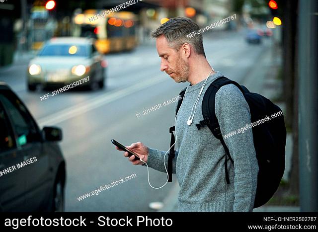 Man on street holding phone
