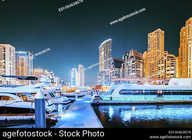 Dubai Marina Port, UAE, United Arab Emirates - Night view Of Dubai Marina Towers And Boats, Yachts Moored Near Pier In Evening Night Illuminations