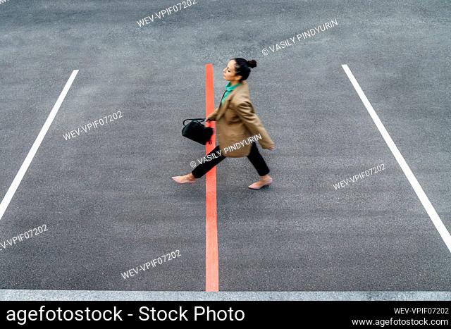 Businesswoman walking over red line at parking lot