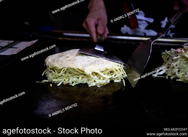Japan, Kyoto, Close-up of chef preparing Okonomiyaki in restaurant