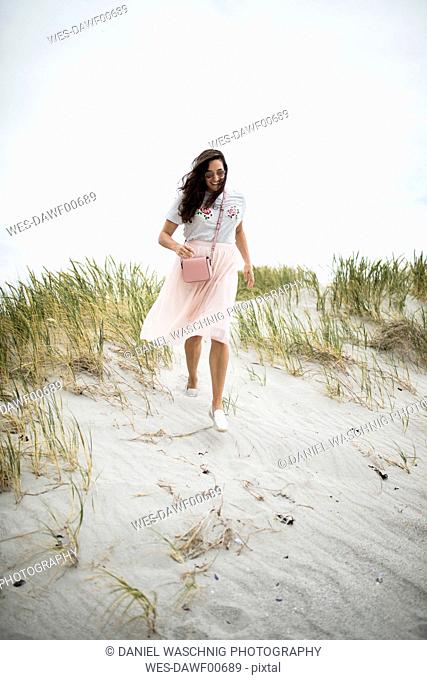 South Africa, Western Cape, Hermanus, happy woman walking in beach dune
