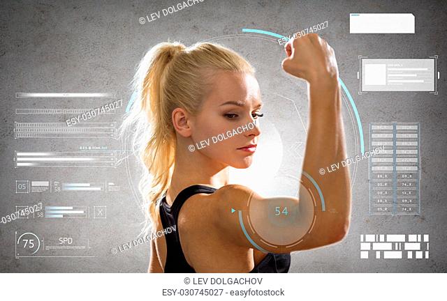 sport, fitness and people concept - young woman posing and showing muscles over gray background