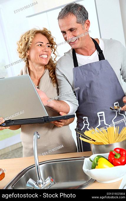 Couple in kitchen looking at recipe on internet