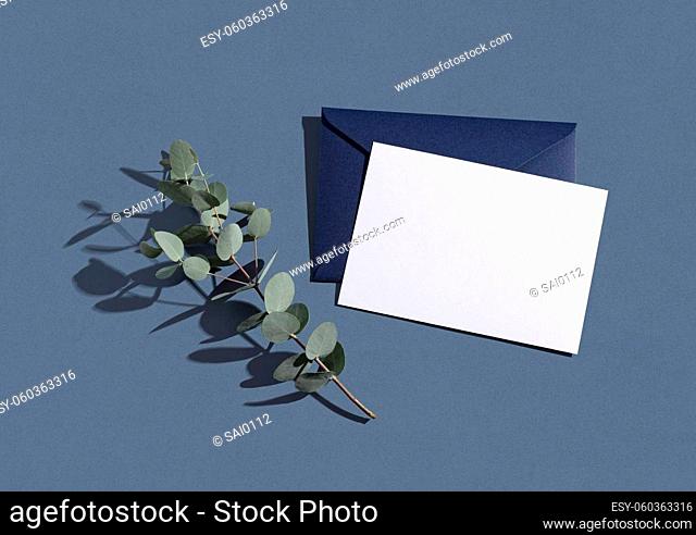This is a mockup of summer wedding stationery. Solid color greeting cards and invitations on a blue background. Eucalyptus leaves