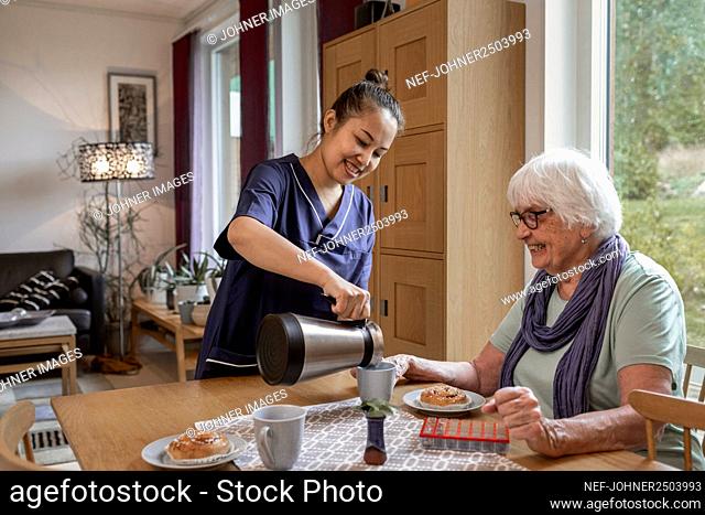 Home carer preparing coffee break for senior woman