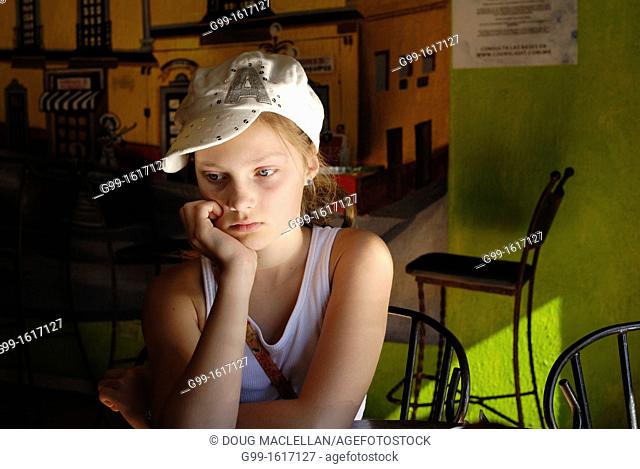 Young girl with hat wating for fod at a restaurant, Nogales, Mexico