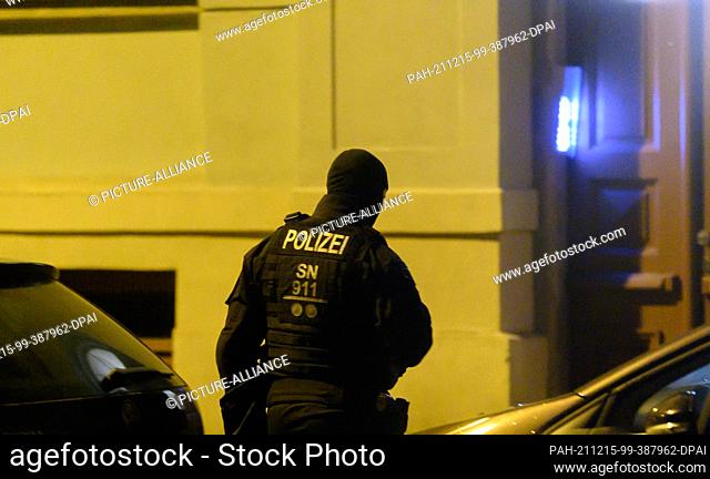 15 December 2021, Saxony, Dresden: A police officer stands in front of a house in the Pieschen district during a raid. After threats against Saxony's Prime...