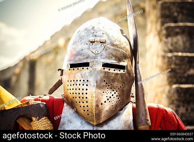 Medieval knight in helmet on ancient wall background