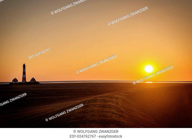 Image of a sunset on the dike of Westerhever in Northern Germany with lighthouse and free space in the sky