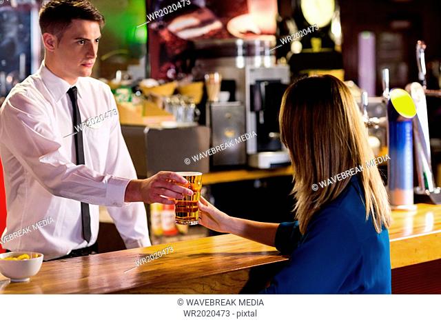 Handsome bartender serving cocktail to woman