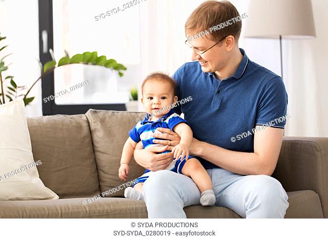 happy father with baby son sitting on sofa at home