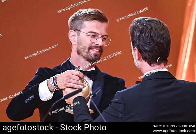 17 September 2021, Saxony, Leipzig: German presenter Joko Winterscheidt (l) receives the ""Goldene Henne"" award from presenter Florian Silbereisen for the...